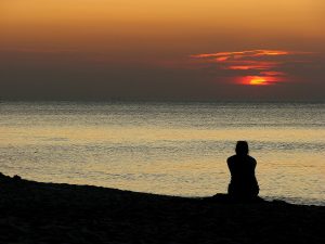 Person sitting looking at sunset sky